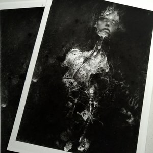 May include: A black and white photo print of a person's face, partially obscured by a white, textured overlay. The image has a distressed, abstract look.