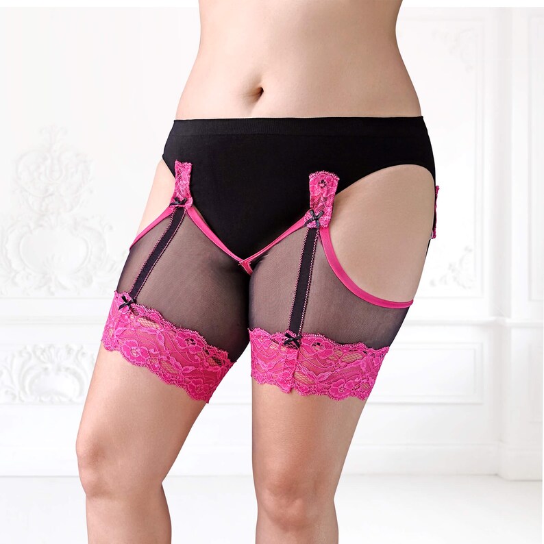 Model in black BaeBliss thigh bands with hot pink lace, lifting back leg to reveal seamless inner thigh design. Slightly front view from below ribs to knees.