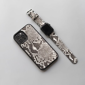 May include: A black iPhone case with a snakeskin pattern and a black Apple Watch band with a snakeskin pattern.