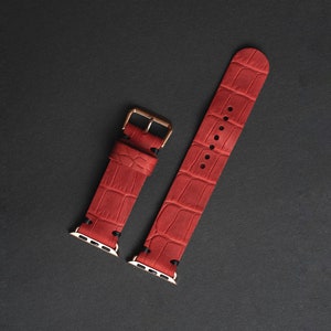 May include: Two red leather watch bands with a crocodile pattern and gold-tone hardware.