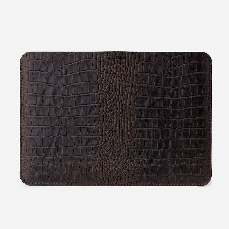 K&ouml;nnte beinhalten: Eine braune Laptoptasche aus Leder mit einem Krokodilpr&auml;gemuster.