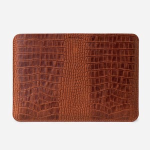 May include: A brown leather laptop sleeve with a crocodile-embossed pattern.