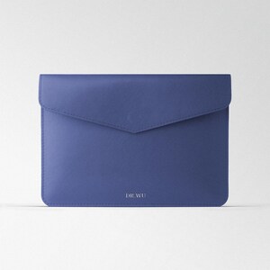 Op de afbeelding: Een blauwe leren envelopclutch met de tekst "DR WU" erop gegraveerd.