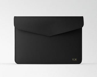 May include: Black leather envelope-style laptop sleeve with a gold embossed "V.N." monogram.