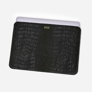 May include: Black laptop sleeve with a textured, crocodile-like pattern. The sleeve has rounded corners and a gold-colored "5555" logo. The laptop is partially visible inside the sleeve.