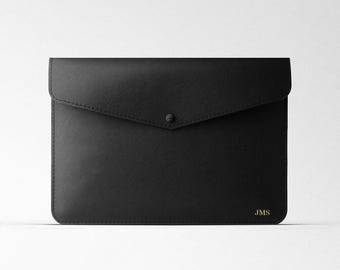 May include: Black leather envelope clutch with a flap closure and a single button. The clutch has a gold embossed monogram "JMS" on the bottom right corner.