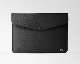 May include: Black leather envelope clutch with a flap closure and a single snap button. The clutch has a gold embossed monogram "LW" on the bottom right corner.
