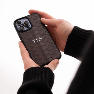 May include: A brown leather phone case with a snakeskin pattern and the word "YES" embossed in white.