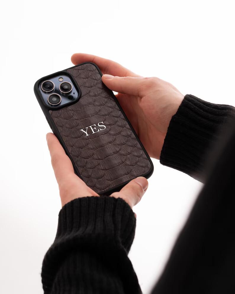 May include: A brown leather phone case with a snakeskin pattern and the word "YES" embossed in white.