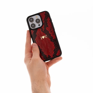 May include: A red and black snakeskin phone case with a gold "I ♥ U" design.