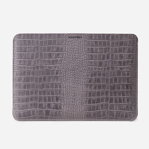 K&ouml;nnte beinhalten: Graue Ledertasche f&uuml;r Laptops mit Kroko-Muster und dem gepr&auml;gten Schriftzug "KARTELL" auf der Vorderseite.