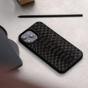May include: A black phone case with a snakeskin pattern. The case has a raised camera bump with three lenses.
