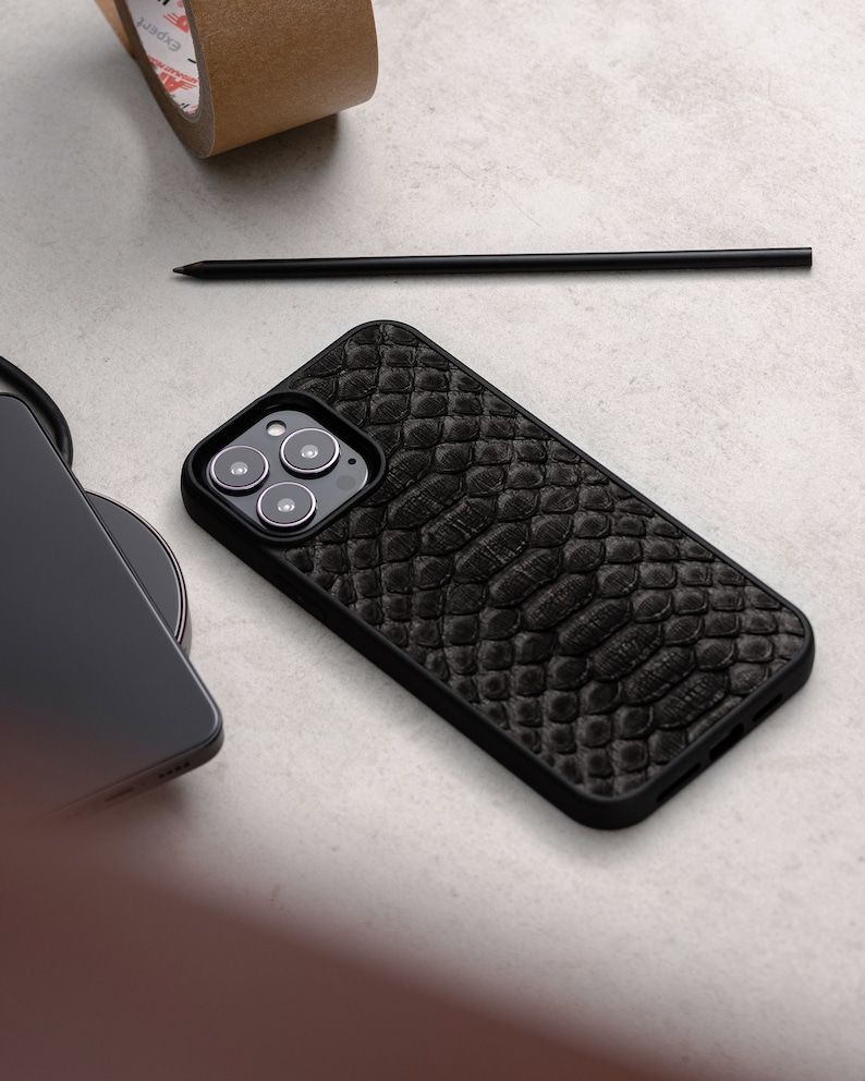 May include: A black phone case with a snakeskin pattern. The case has a raised camera bump with three lenses.
