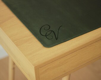 May include: A light wood desk with a drawer and a green leather desk pad with the initials "CV" embossed on it.