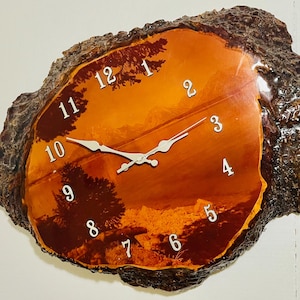 May include: A distinctive wall clock made from a tree trunk section. The clock face displays a landscape scene with white numerals and hands. The natural wood edge gives a rustic feel to this decorative timepiece.