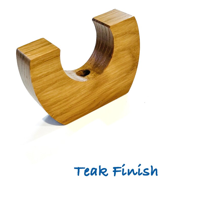 May include: A crescent-shaped wooden candle holder with a light brown grain and a smooth finish. The object features a circular opening at the center for a candle. The text Teak Finish is printed in blue below the wooden candle holder.