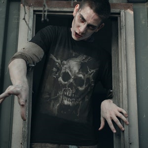May include: A man with a skull graphic on his black t-shirt looks out of a window. He has a pale complexion and dark hair. His expression is intense.