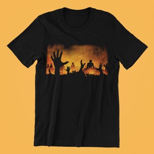 Könnte beinhalten: Schwarzes T-Shirt mit einem grafischen Druck einer Gruppe von Silhouetten, die aus einem feurigen orangen Hintergrund herausragen.