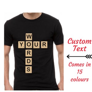 May include: Black t-shirt featuring a graphic of the word "WORDS" spelled out using Scrabble tiles. The text "Custom Text" is written in red above the graphic. The text "Comes in 15 colours" is written below the graphic.