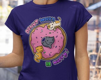 May include: A purple t-shirt with a donut and three cats on it. The donut has pink frosting and sprinkles. The text on the shirt says "Donut Worry Be Happy!"