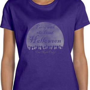 May include: Purple t-shirt with a white graphic of a moon with the text "Party with the Dead Halloween One Night Only!"