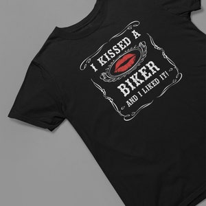 Peut inclure: T-shirt noir avec un motif graphique blanc qui dit "J'ai embrass&eacute; un motard et j'ai aim&eacute; &ccedil;a !" avec une empreinte de rouge &agrave; l&egrave;vres rouge.