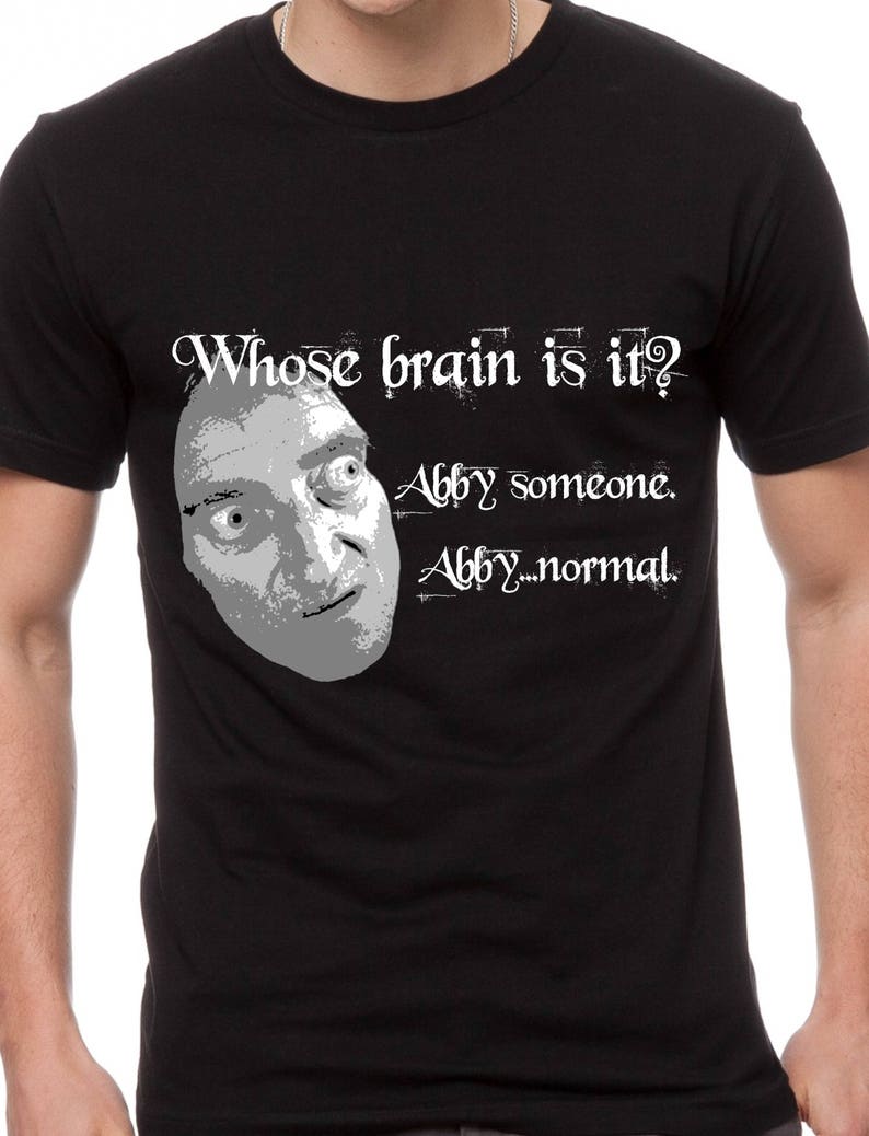 May include: Black t-shirt with a white graphic of a man's face and the text "Whose brain is it? Abby someone. Abby...normal."