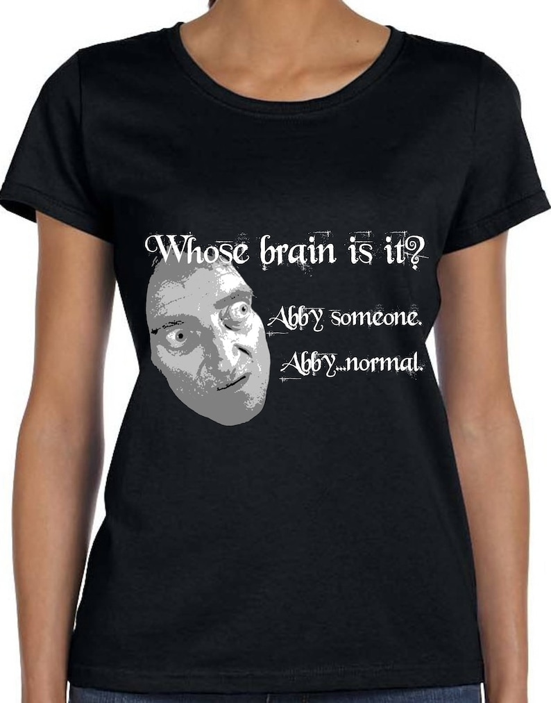 May include: Black t-shirt with a white graphic of a man's face and the text "Whose brain is it? Abby someone. Abby...normal."