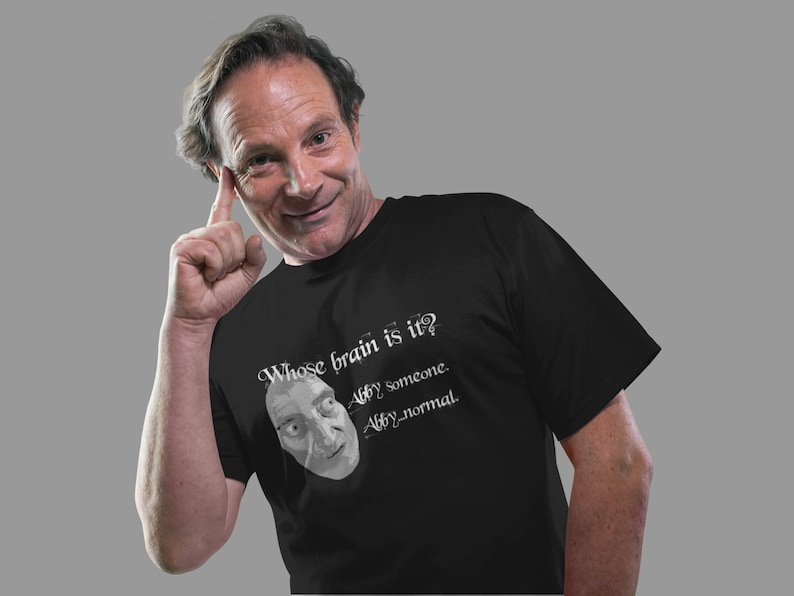 May include: A black t-shirt with a white graphic print of a man's face and the text "Whose brain is it?  Abby someone. Abby normal."