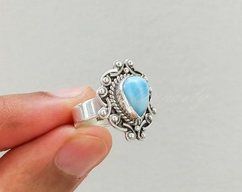 May include: A silver ring with a teardrop-shaped blue gemstone set in a detailed silver design.