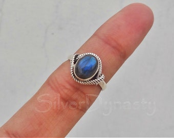 May include: A silver ring with a blue oval labradorite gemstone. The ring has a twisted band design.