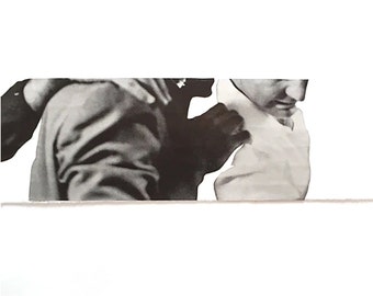 May include: A black and white photograph of two people, one with their arm around the other's shoulder. The person in the foreground is wearing a white shirt and the person in the background is wearing a dark jacket.