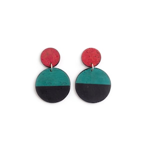 May include: A pair of earrings with a black and teal circle design with a smaller red circle on top.