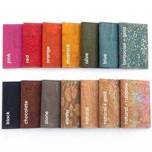 Pu&ograve; includere: Una collezione di portafogli in sughero in vari colori, tra cui rosa, rosso, arancione, senape, oliva, blu e turchese con dettagli dorati. Altri colori sono nero, cioccolato, pietra, terroso, naturale e naturale con dettagli oro e arcobaleno. Ogni portafoglio &egrave; etichettato.