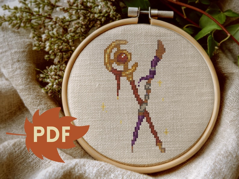 Puede incluir: Bordado de punto de cruz en un aro de madera. El dise&ntilde;o presenta una figura estilizada con un bast&oacute;n, en tonos marr&oacute;n, morado y dorado, con peque&ntilde;os acentos de estrellas amarillas. El texto "PDF" est&aacute; en un gr&aacute;fico en forma de hoja.