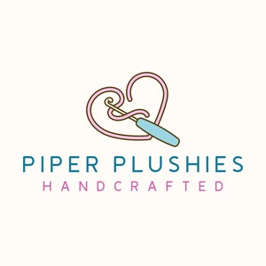 May include: A pink heart shape with a blue crochet hook going through it. The text "PIPER PLUSHIES HANDCRAFTED" is below the heart.