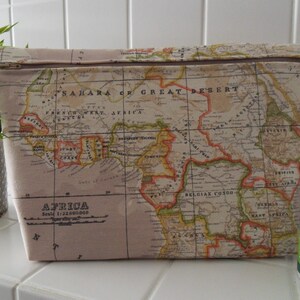 Könnte beinhalten: Eine beige Reißverschlusstasche mit einer gedruckten Vintage-Karte von Afrika. Die Karte zeigt die Sahara, Französisch-Westafrika, Belgisch-Kongo und Ostafrika. Die Tasche ist aus Stoff und hat einen Reißverschluss.