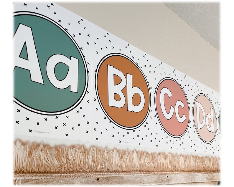 This image shows a close-up of fun font boho alphabet posters posted at the top of a classroom.