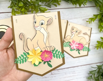 May include: A brown and beige banner featuring a cartoon lion cub with yellow and pink flowers. The banner is decorated with green leaves.