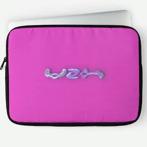 Può includere: Una custodia per laptop rosa con un designo di glitter argentati che dice "W2A" in un font stilizzato.