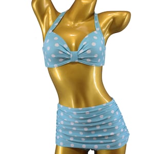 Könnte beinhalten: Ein blauer und weißer gepunkteter Bikini mit einem Neckholder-Oberteil und einem hoch taillierten Rock.