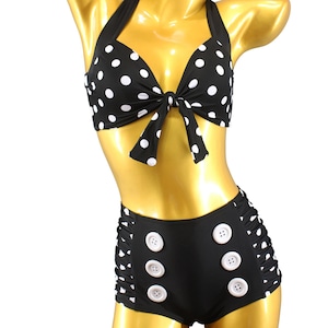 May include: Black and white polka dot bikini top with a bow tie and matching high-waisted bottoms with white buttons.