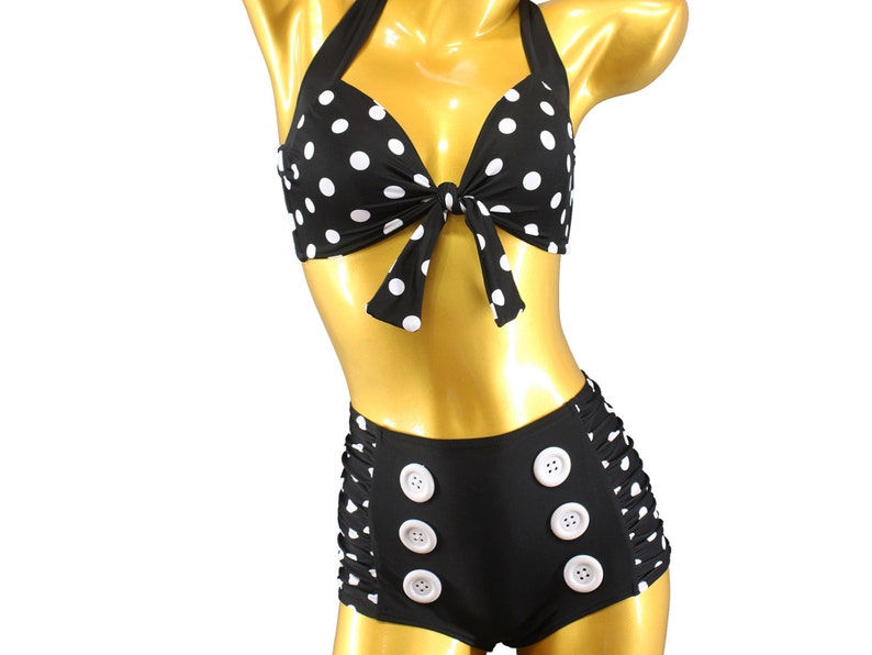 May include: Black and white polka dot bikini top with a bow tie and matching high-waisted bottoms with white buttons.