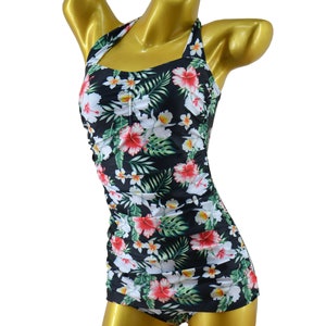 May include: A black swimsuit with a tropical floral print featuring red, white, and green flowers. The swimsuit has a halter neck strap and a fitted silhouette.
