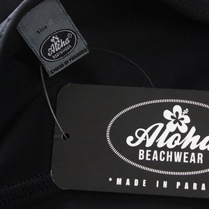 May include: Black and white label with the text "Aloha Beachwear" and a hibiscus flower graphic. The label also says "Made in Paradise".