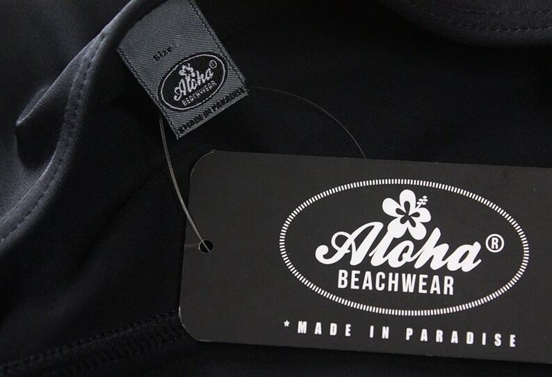 May include: Black and white label with the text "Aloha Beachwear" and a hibiscus flower graphic. The label also says "Made in Paradise".