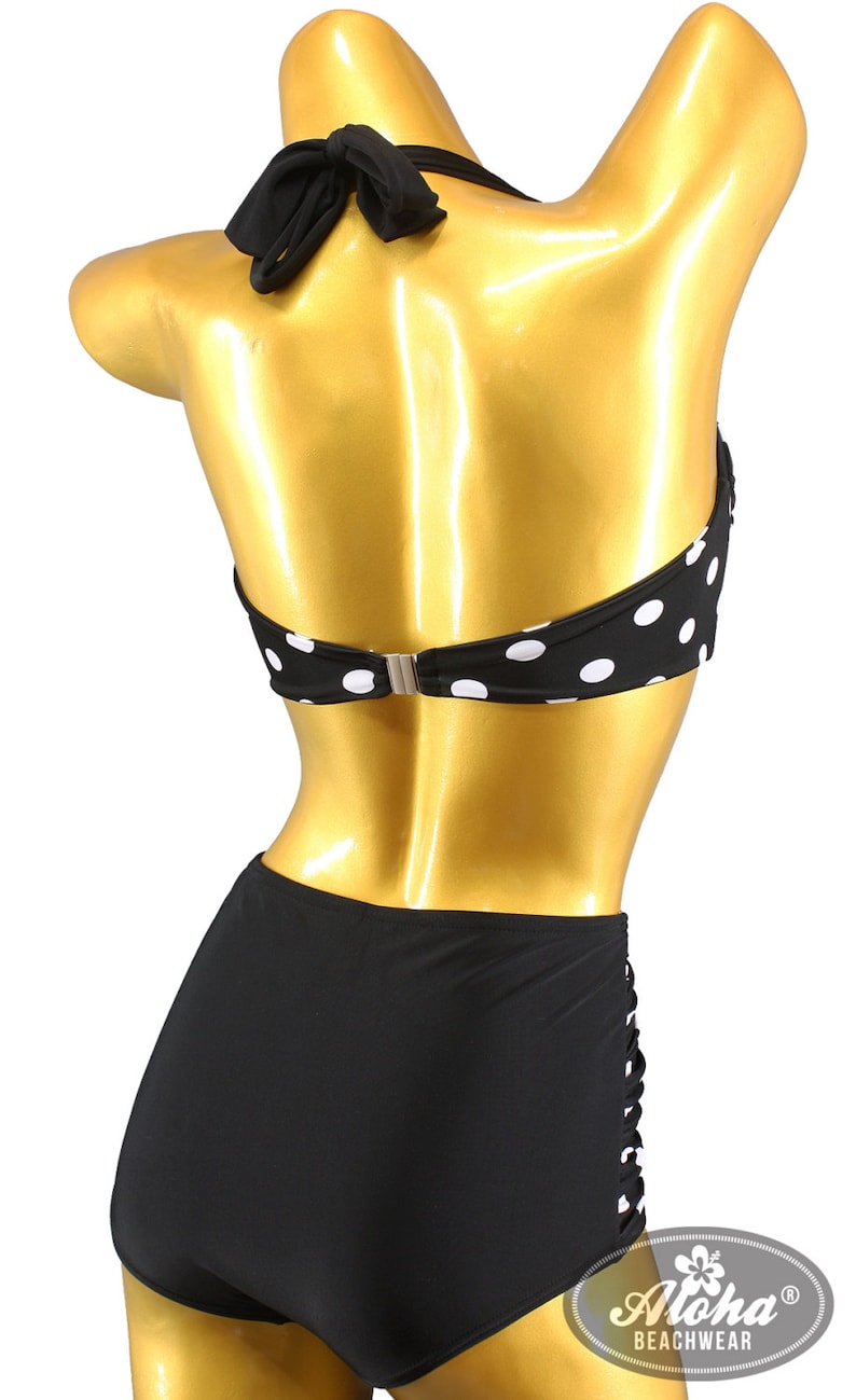 May include: Black and white polka dot bikini top with a black halter strap and a black high-waisted bottom. The bikini bottom has a cut-out detail on the side. The bikini is labeled "Aloha Beachwear".