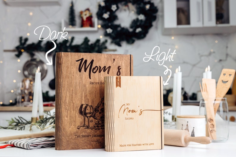 May include: Two wooden recipe boxes with engraved text. The larger box is dark brown with the text "Mom's Recipe Box" and a design of wine glasses. The smaller box is light brown with the text "My Mom's Recipes" and the text "Made for Heather with Love".