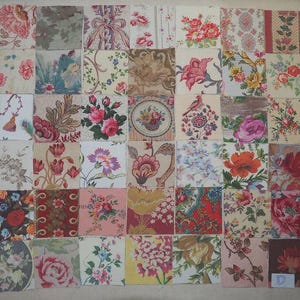 Op de afbeelding: Een patchworkquilt bestaande uit talrijke stoffen vierkanten, elk met een uniek bloemenpatroon. De vierkanten tonen een verscheidenheid aan kleuren, waaronder roze, rood, blauw en geel, waardoor een levendig en visueel aantrekkelijk ontwerp ontstaat. De quilt is waarschijnlijk handgemaakt.