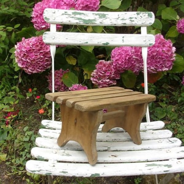 Un petit banc ancien en bois à lattes , repose pied